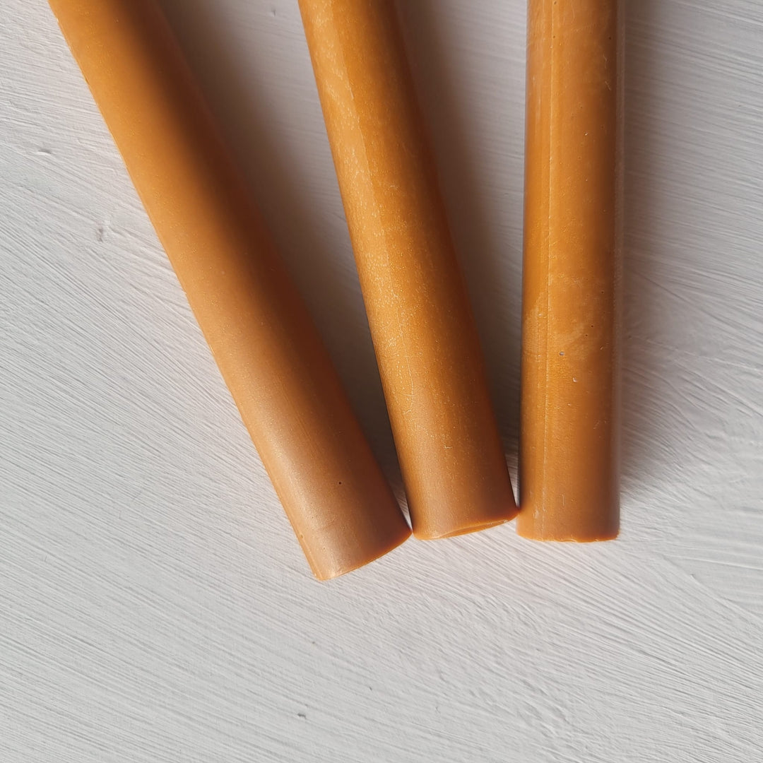 Close-up of three sienna-colored 11mm sealing wax sticks on a white surface, showcasing smooth texture and handmade quality.